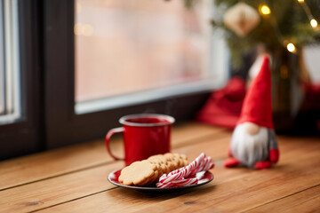holidays, decoration and celebration concept - close up of christmas gnome, cup of coffee in red...