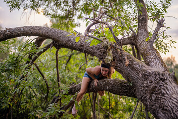 A fit woman trains outdoors, warming up on a tree. She exercises with grace, showcasing her strength and flexibility. Enjoying the green park, she embodies a healthy and active lifestyle.