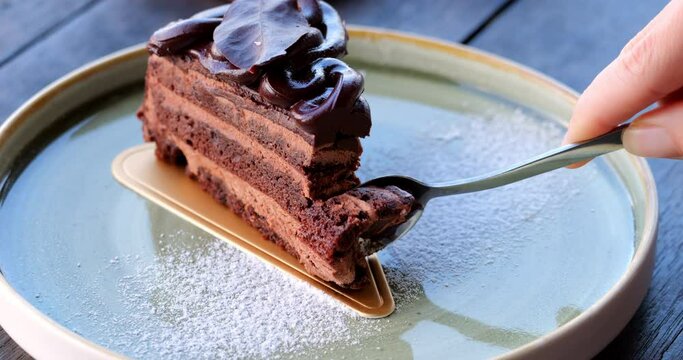 Indulge in the irresistible pleasure of scooping a luscious slice of chocolate cake with a teaspoon in this captivating slow-motion close-up, highlighting every delightful moment