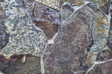 Close-up of a rock wall with light gray color, and it has a smooth, weathered texture. There are a few small cracks and fissures in the rock, but it is overall in good condition
