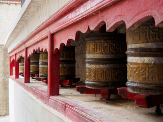 Metal Prayer Wheels at Shey Monastery or Gompa. A mantra 'Om Mani Padme Hum' was embossed on brass surface. Mantra is in Tibetan script and meaning is 'Praise to the Jewel in the Lotus&rsquo;.