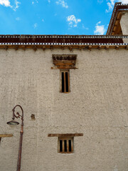 Outside wall of Shey Monastery Gompa, see cracks on stucco surface and old technique windows built. Eaves of the building is unique style, made and decorated with wood.