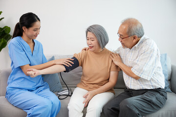 caregiver or nurse measure blood pressure to senior woman on sofa