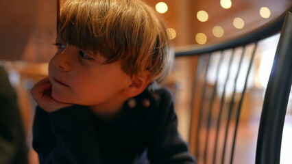 Hungry Anticipation of Cheerful Boy Sitting with hand in chin, Patiently Awaiting Meal in Restaurant
