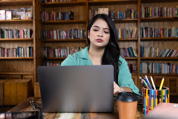 Beautiful young business woman girl student studying or explaining on video call on laptop in school or collage library or working in corporate office searching for information on internet or books
