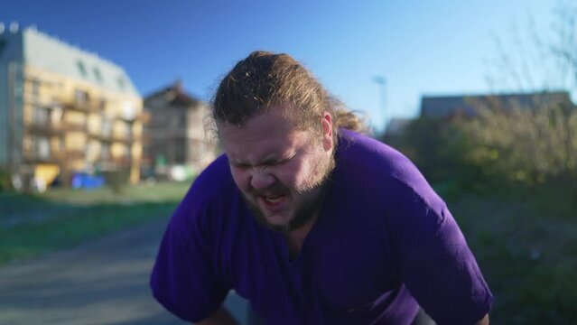 One tired overweight young man recovering from run. Exhausted fat person taking a deep breath. Lifestyle exercise taking a break outdoors