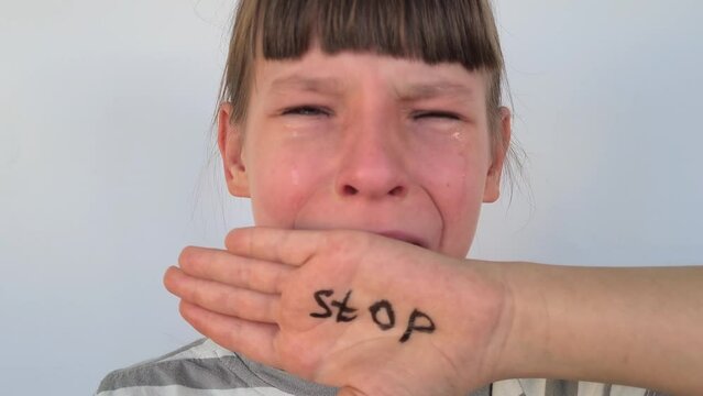 Little girl extends her hand the word stop and shows gestures of protest against domestic violence. Young teenage child speaks out against discrimination and abuse at school