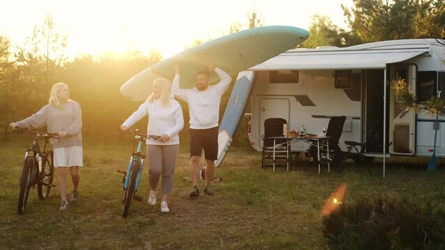 Happy family relaxing in nature near motorhome at sunset. Travelling by car for recreation