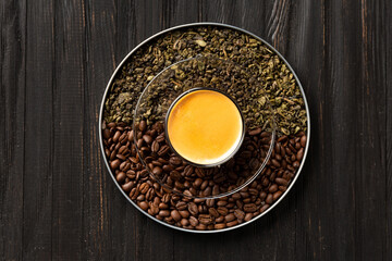 Composition of green tea, coffee beans and coffee in a cup on a dark background top view.