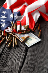 American flag, dollars, bullets, cartridges, ammunition on a black wooden background