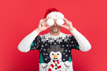 Santa with bauble, christmas ball. Portrait of middle aged man in sweater isolated over red background. Concept of holidays, happiness, emotions and Christmas celebration.
