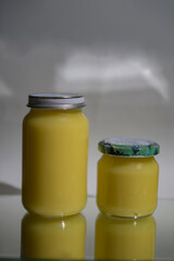 Ghee clarified butter desi in glass jar with rosemary on natural background.