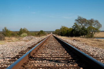 A set of railroad tracks disappearing on the distant horizon as they lead out into a western...