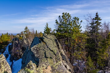 The stone slope of the mountain with trees on the background of the sky in spring