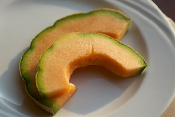 Two slices of juicy melon on a white ceramic plate.