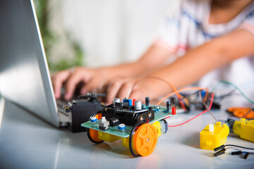 Obraz na płótnie Canvas Asian kid boy learns coding and programming with laptop for Arduino robot car, Little child students typing code in computer with car toy, STEAM education AI technology course school learning