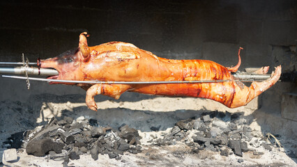 Pig carcass on a spit roasted over an open fire. - obrazy, fototapety, plakaty
