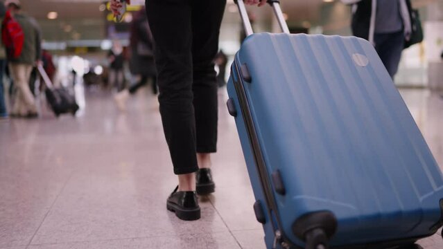 woman in business attire walks with suitcase on airport moving walkway, implying travel, independence, and professional lifestyle. Season indeterminate, focus on action and concept of business travel