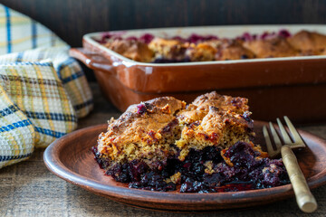 Slice of fresh baked blueberry cobbler on plate with fork. Homemade berry cobbler, closeup