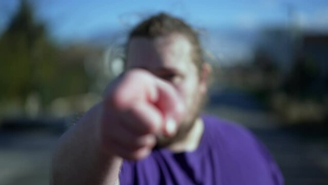 One angry judgemental man pointing finger at camera standing outside. One chubby Person points hand accusing. POV accusation concept