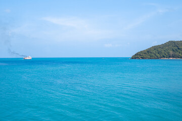 The blue surface of the sea with a ship sailing in the distance. Travel and tourism