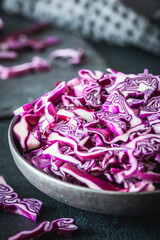 Obraz na płótnie Canvas Fresh red cabbage, cut into pieces and strips, on gray table