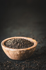 Chia seed in a rustic bowl on dark background