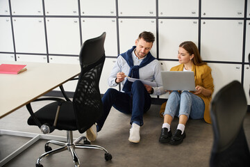 Managers with laptops and work documents are located on floor