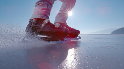 LENS FLARE, CLOSE UP: Man brakes and stops while ice skating on a frozen pond