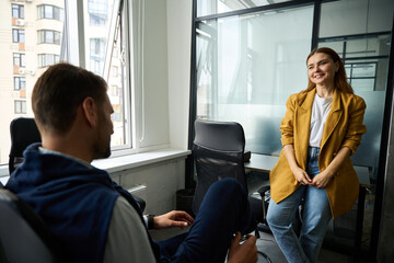 Young woman in yellow jacket communicates with colleague in office