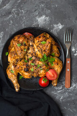Chicken tabaka, national Georgian dish. Whole chicken with golden fried crust on a dark background.