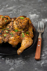 Chicken tabaka, national Georgian dish. Whole chicken with golden fried crust on a dark background.