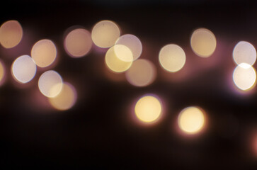 Blurred out-of-focus bright lights of a garland on a dark background close-up