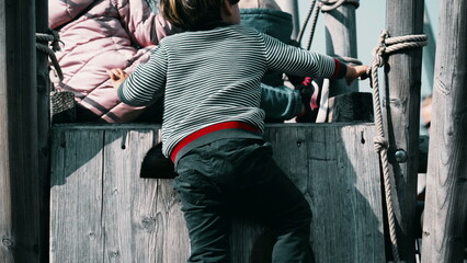 Child Engaging in Active Play, Climbing on Playground During Autumn at a Public Park
