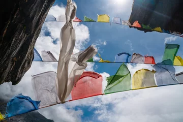 Papier Peint photo Makalu Holy Buddhist praying multicolored flags with mantras flapping and waving on the strong wind with blue sky with white clouds background. Makalu Barun National Park, Mera peak climbing route, Nepal