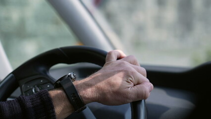 Close-up hand holding vehicle steering wheel driving car on road