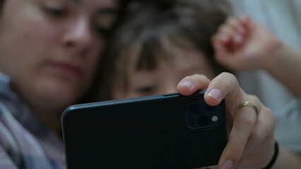 Close-Up of Engrossed Mother and Son in Bed, Focused on Online Entertainment Content via Cellphone