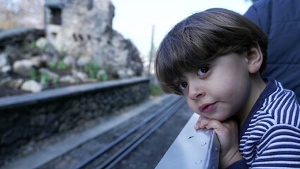 Child riding miniature train at Swiss vapeur observing railroad view, small boy leaning from wagon in motion