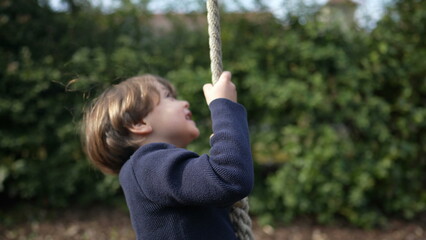 Child sliding down on wire rope reaching the end of the line - holding tight on grip while having...