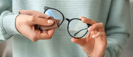Woman wiping her eyeglasses, closeup