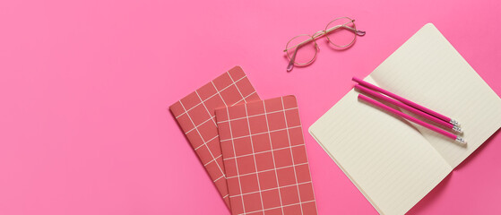 Eyeglasses with notebooks and pencils on pink background with space for text