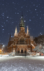 Picturesque gothic revival St Joseph church on Podgorski square during snowy night, Krakow, Poland