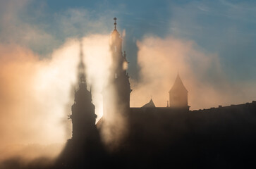 Krakow, Poland, Wawel cathedral towers shrouded in the fog, sunlit in the morning - obrazy, fototapety, plakaty