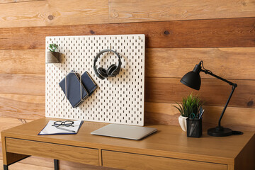 Modern workplace with pegboard near wooden wall in office