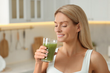 Woman drinking fresh celery juice in kitchen