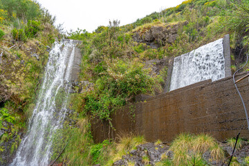 Obraz premium Waterfalls in the form of a cascade in a levada channel to transport irrigated water to another channel, Portuguese island of Madeira.