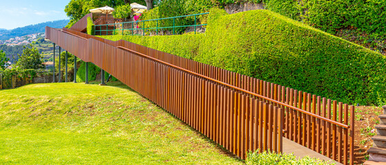 ramp with a wooden fence for people in wheelchairs to move inside the botanical garden on the...