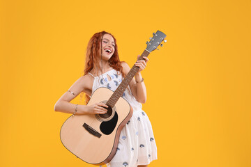 Beautiful young hippie woman playing guitar on orange background