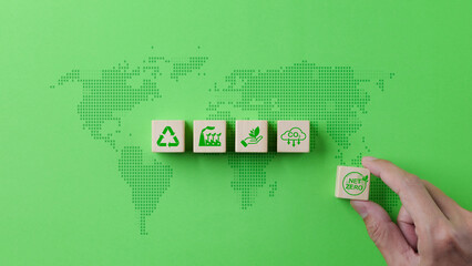 Net zero emission and carbon neutral 2050 concept. Hand puts wooden cube block with net zero icons...