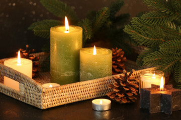 Christmas composition with burning candles and fir branches on dark background.